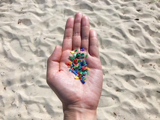hand full of plastic pieces at the beach