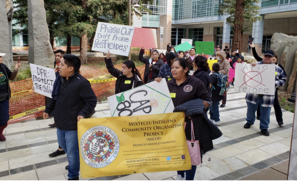Farmworker families holding signs in front of the California Environmental Protection Agency