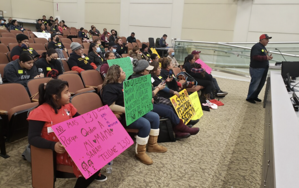 People holding signs and speaking about 1,3-D use at a public hearing before the Department of Pesticide Regulation.